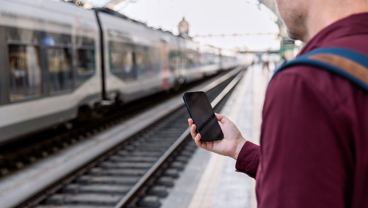 Traveler on a train platform looking at their phone